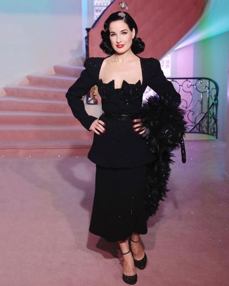 Dita Von Teese in a black dress poses for a picture.